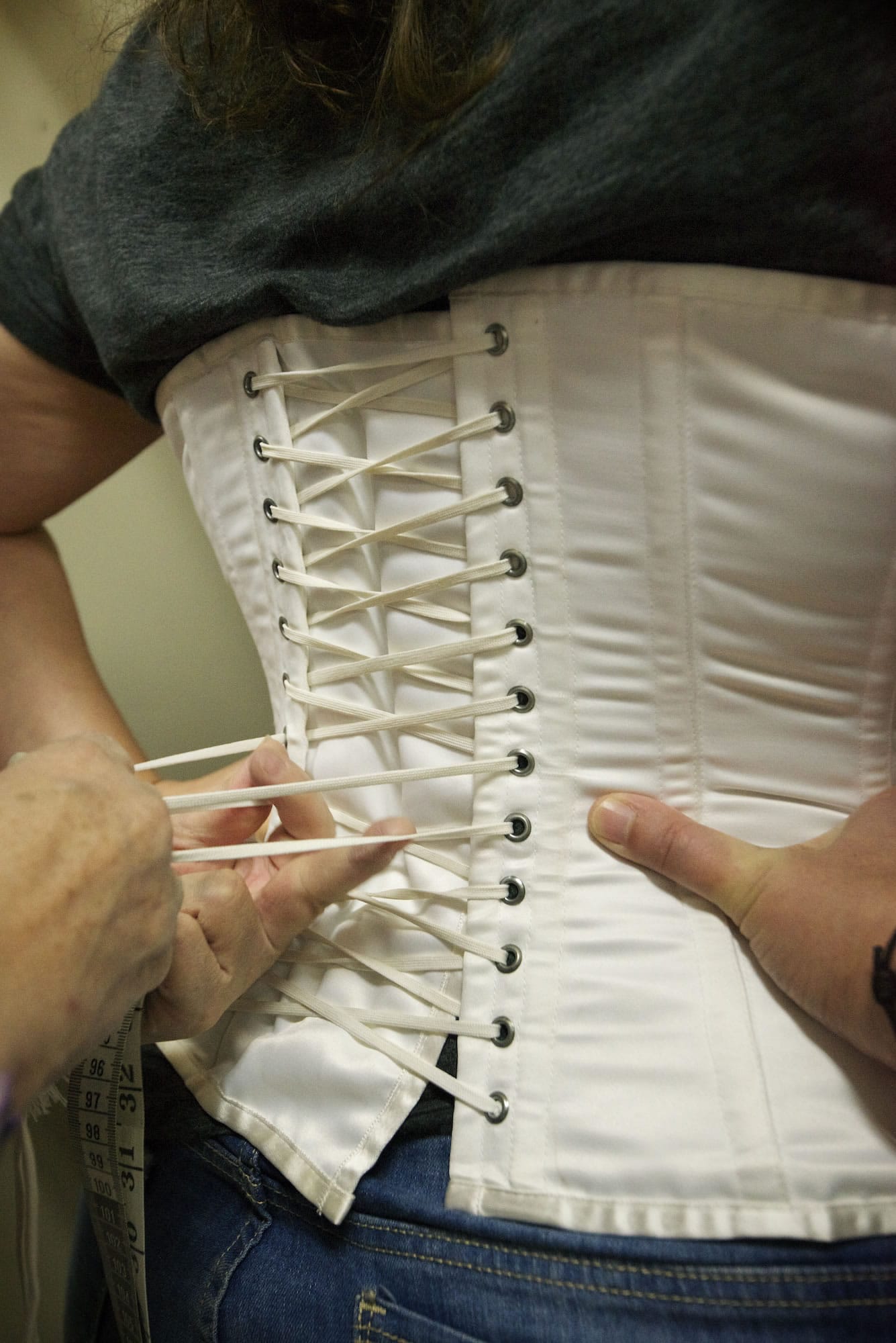 Eileen Trestain, head of the costume department at the Fort Vancouver National Historic Site, tightens a corset in preparation for a dress fitting for Heidi Pierson, a National Park Service cultural resource specialist, Wednesday.