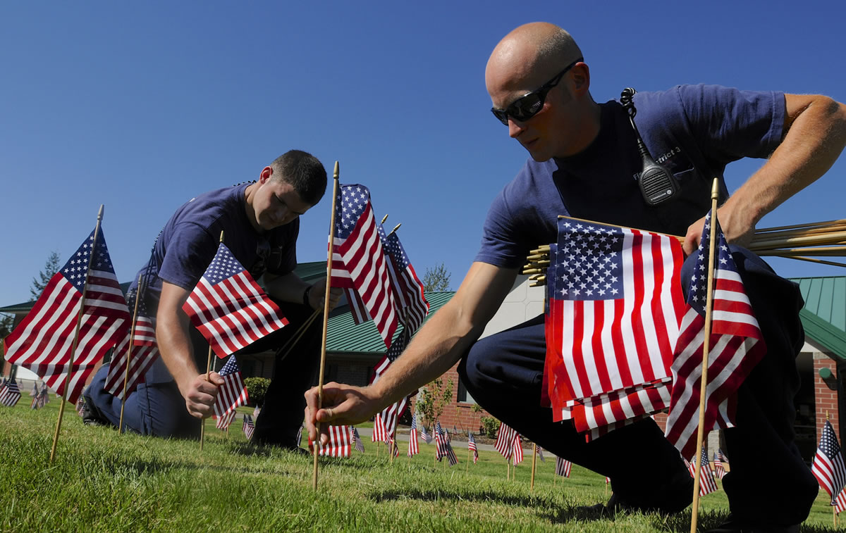 Ryan Beickel, left, an intern, and District 3 firefighter Andrew Wolf plant some of the 300 flags honoring the fatalities on Sept.
