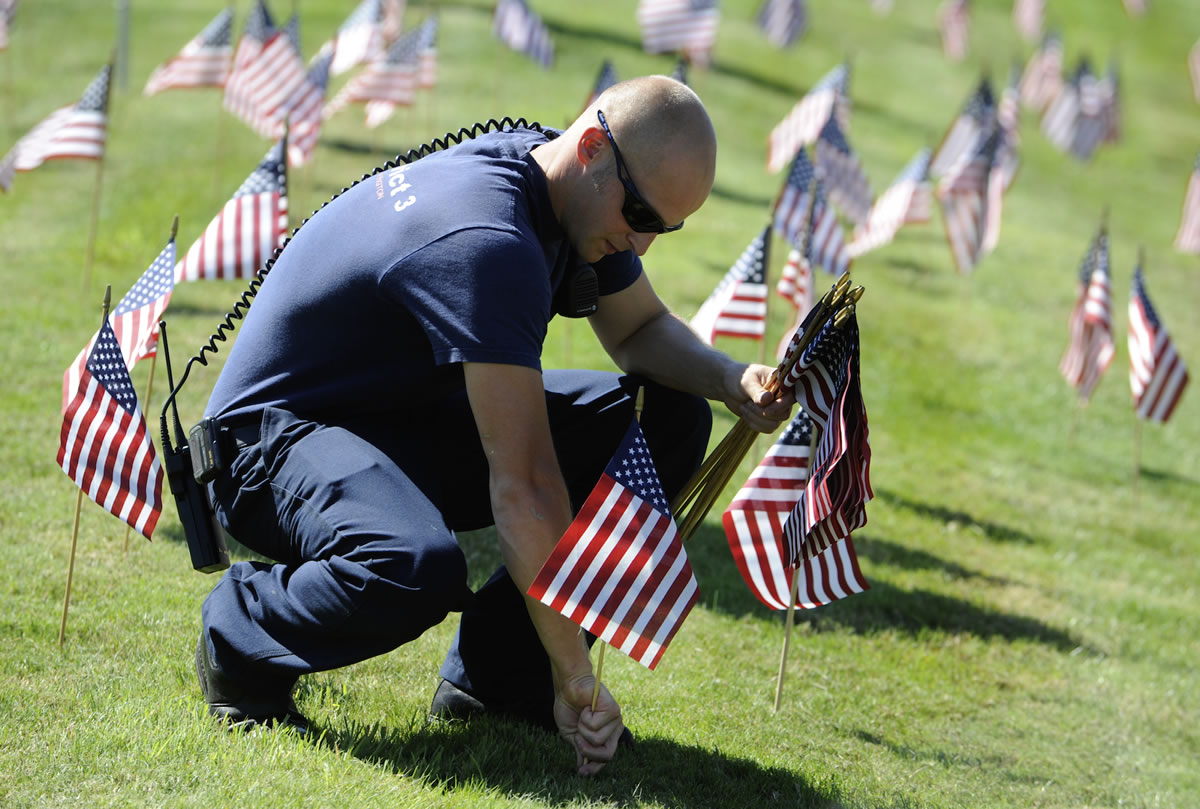 District 3 firefighter Andrew Wolf sets some of the more than 300 flags placed at the fire station ahead of today's  9/11 observance in Hockinson.