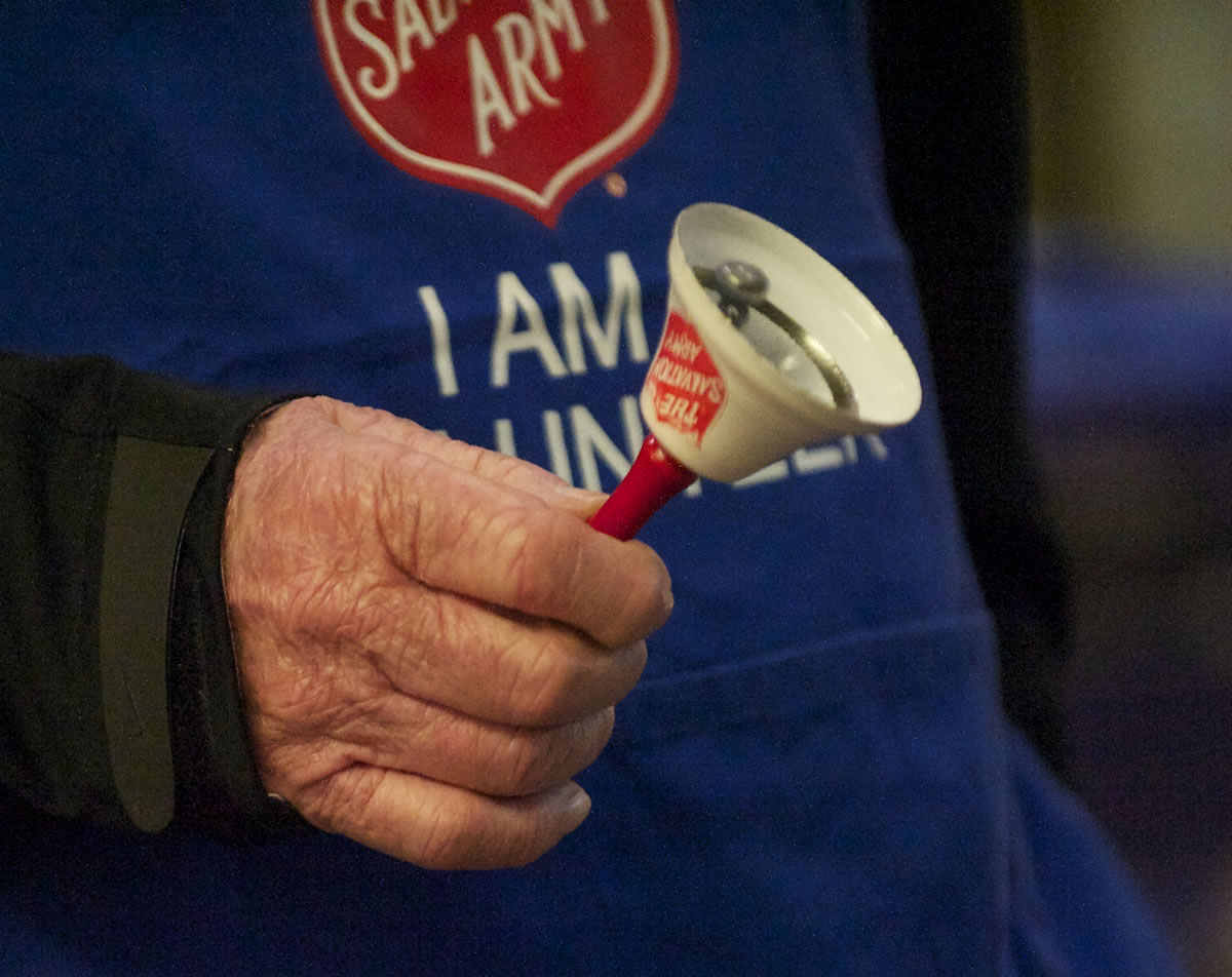 Salvation Army bell ringer Chuck Mulligan, in the blue apron, who has been volunteering for the seasonal position for about 50 years, collects donations at Fred Meyer in east Vancouver  on Dec.