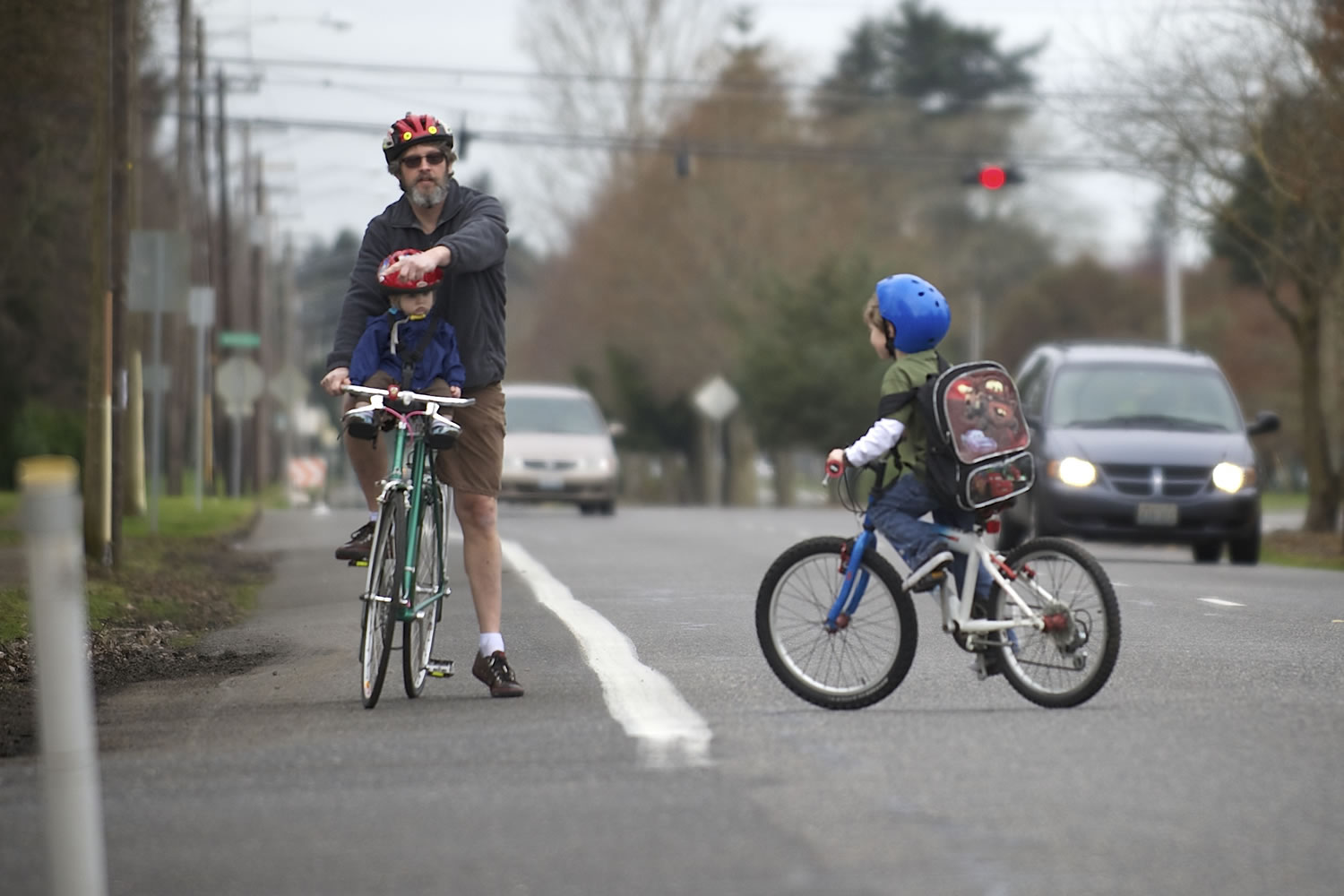 Paul Deming helps his son, Brian, 6, cross MacArthur Boulevard on March 13. Paul Deming and other cyclists have safety concerns along the corridor because of the large number of lanes and the speed of traffic.
