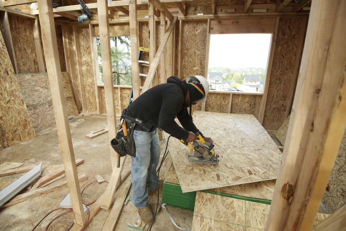 Carpenter Miguel Vargas cuts a sheet of particle board while helping build a home at the Sunrise Ridge subdivision in the Hazel Dell area.