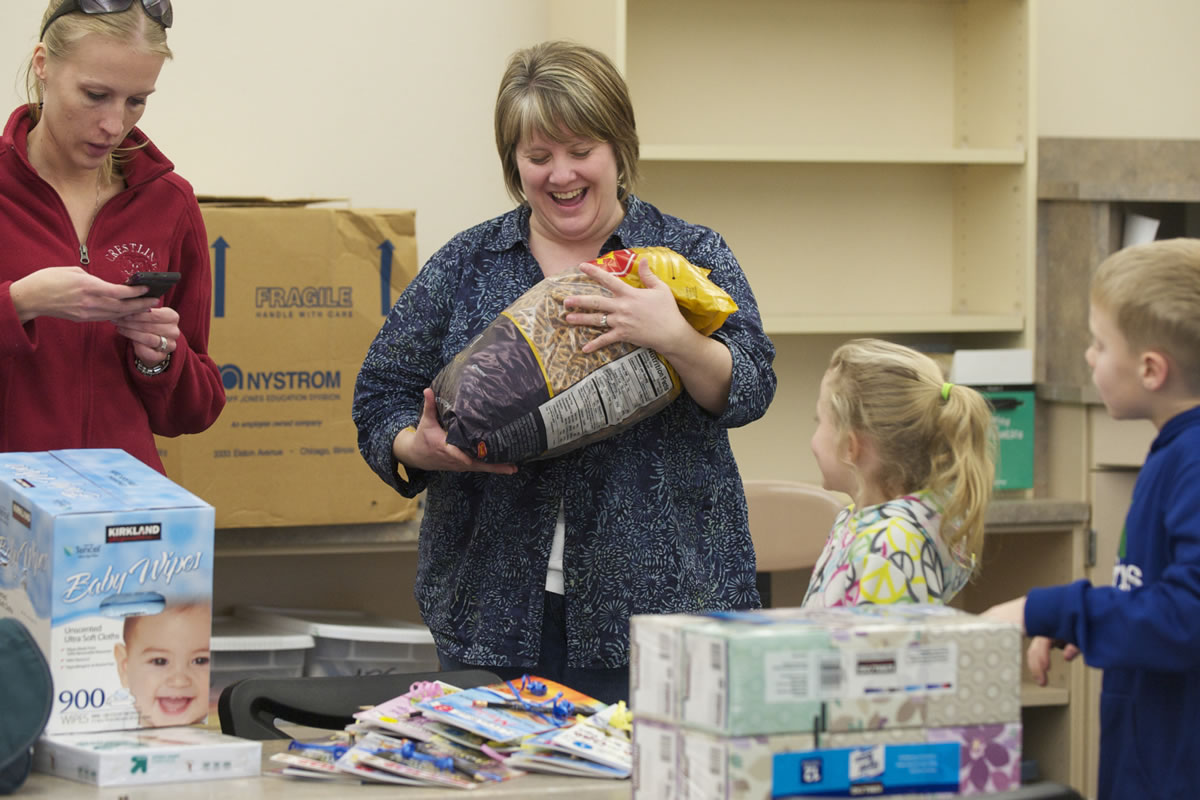 Crestline Elementary second-grade teacher Katie Van Ness receives a bag of snacks from her students, Maddie Burris, 7, and brother Devon Burris, 7, as she readies her new classroom at Columbia Valley Elementary.