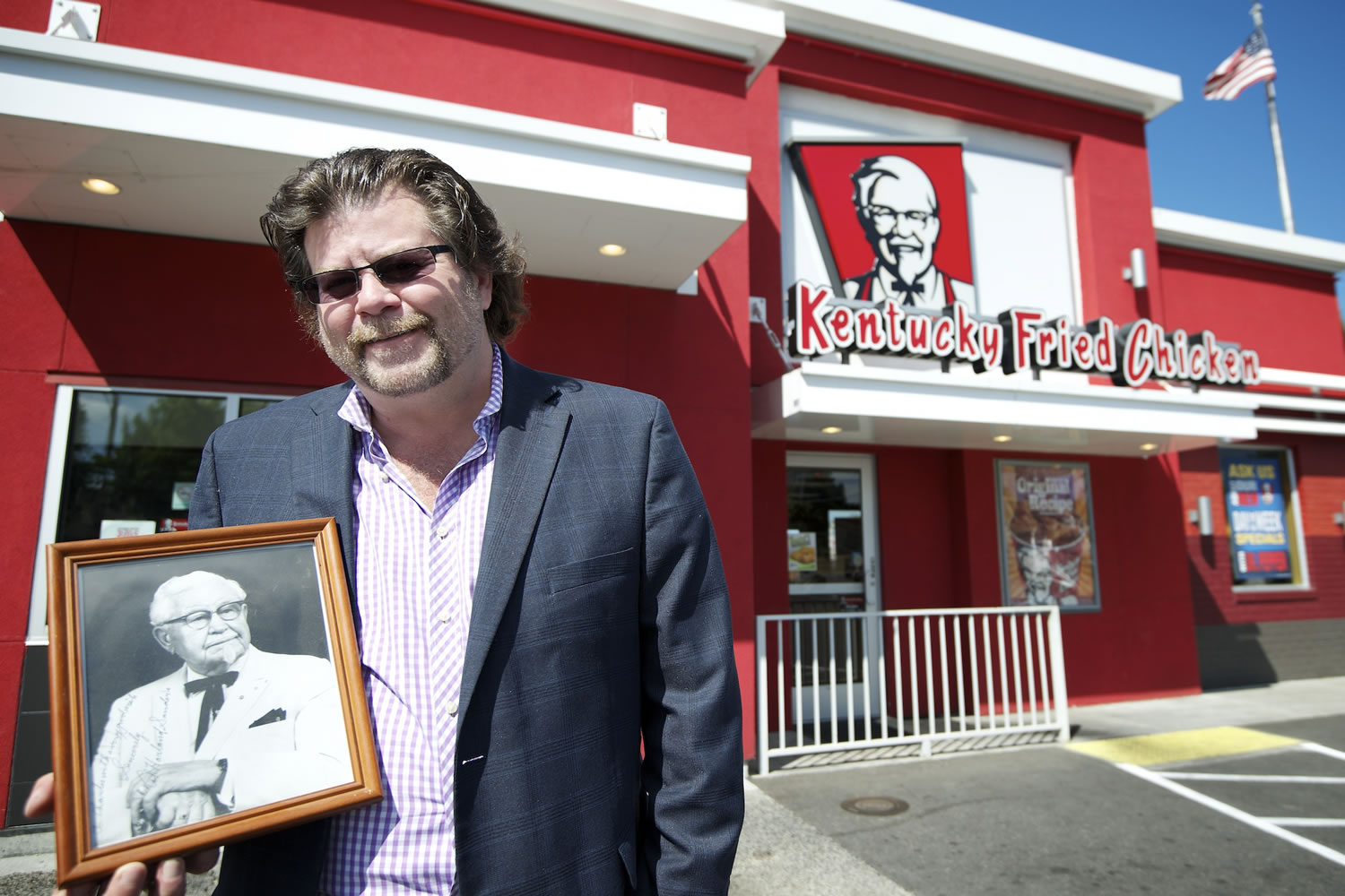 Scott Dickinson, former owner of eight area Kentucky Fried Chicken restaurants, holds a black-and- white photo of KFC founder Col. Harland Sanders. Dickinson is liquidating his KFC business, which operated under the name Dickinson Northwest Inc. Two of the Vancouver restaurants, including the one shown here at 1203 N.E.