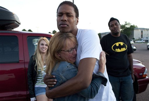 Judy Goos, second from left, hugs her daughters friend, Isaiah Bow, 20, while eye witnesses Emma Goos, 19, left, and Terrell Wallin, 20, right, gather outside Gateway High School where witness were brought for questioning Friday, July 20, 2012 in Denver.