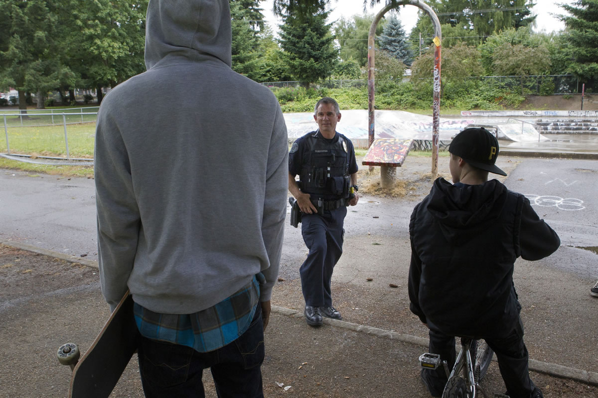 Vancouver police Cpl. Duane Boynton approaches two young men at Water Works Park last week. One of the boys, who identified himself only as Kyle, said that a group at the park whistles when they're about to attack someone.