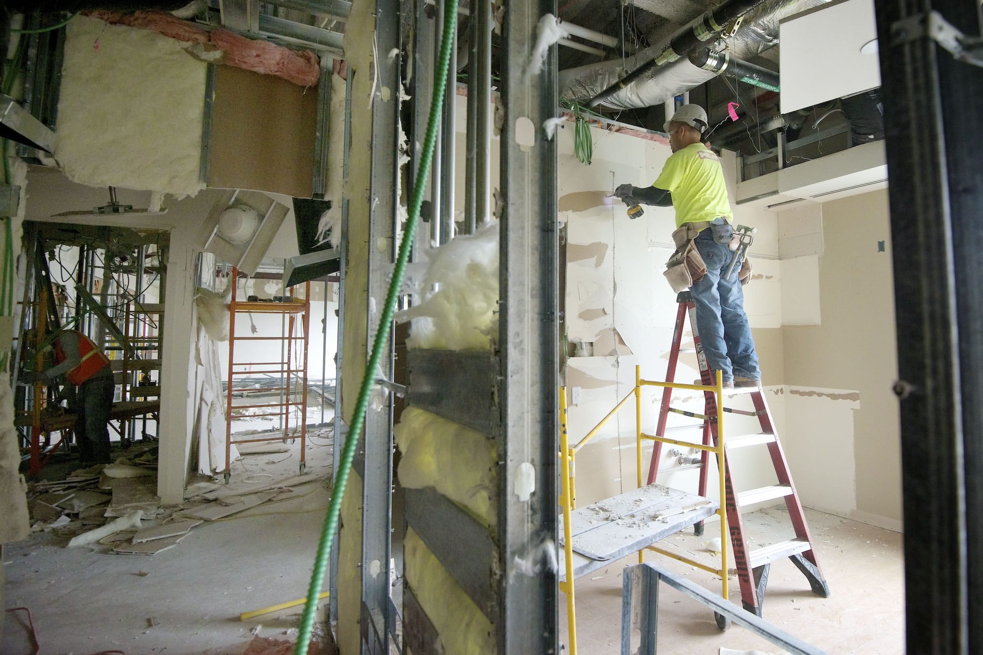 Pablo Rodriguez, right, of Harliens Drywall, removes sheetrock as part of a project to enable Legacy Salmon Creek Medical Center to handle Kaiser-insured patients once a seven-year contract takes effect Oct.