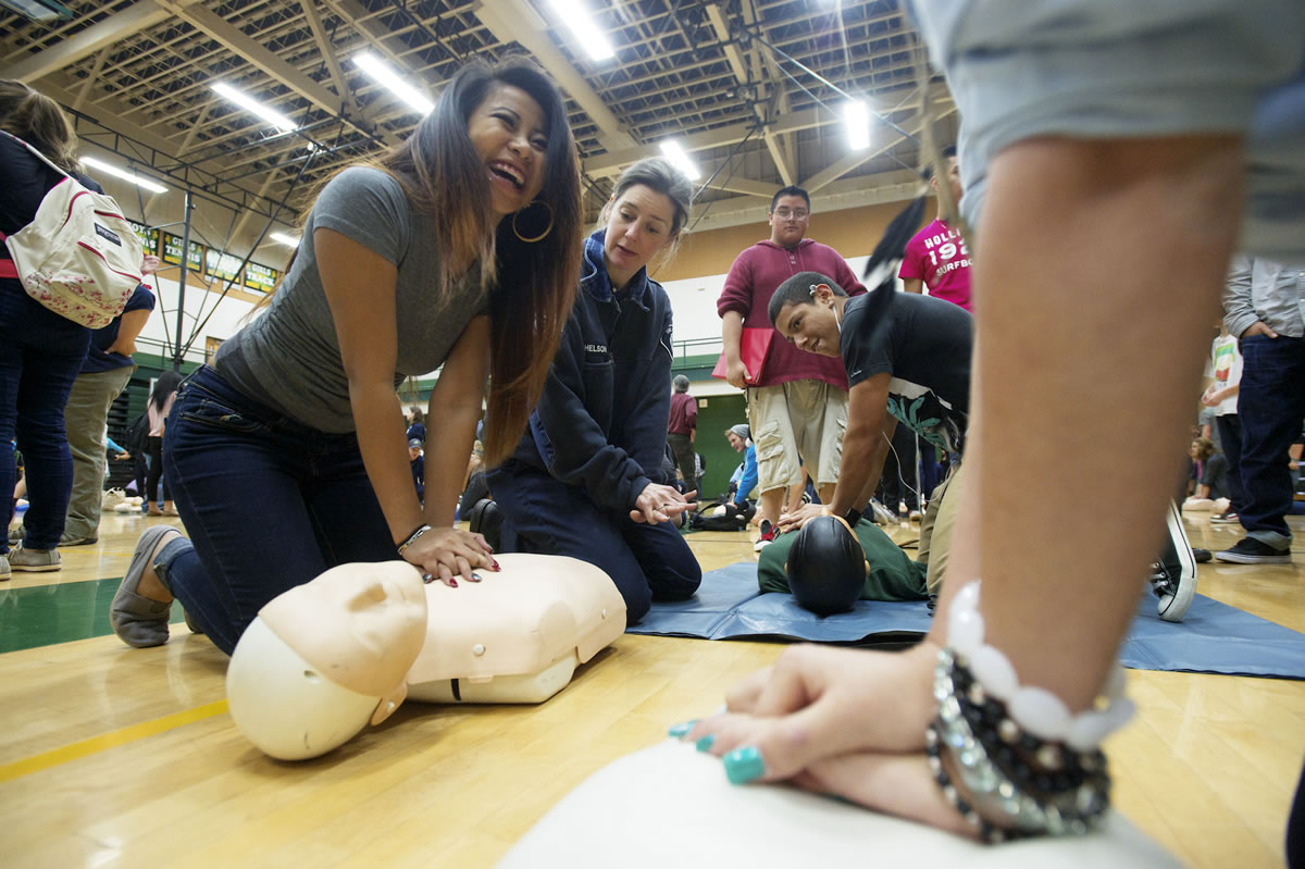 Photos by Steven Lane/The Columbian
Chelsea Labitad, 18, left, a senior at Evergreen High School,  receives a hands-only CPR training session Friday from Fire District 6 public education coordinator Sarah Mitchelson. Several hundred students received a short orientation and then hands-on training with mannequins.