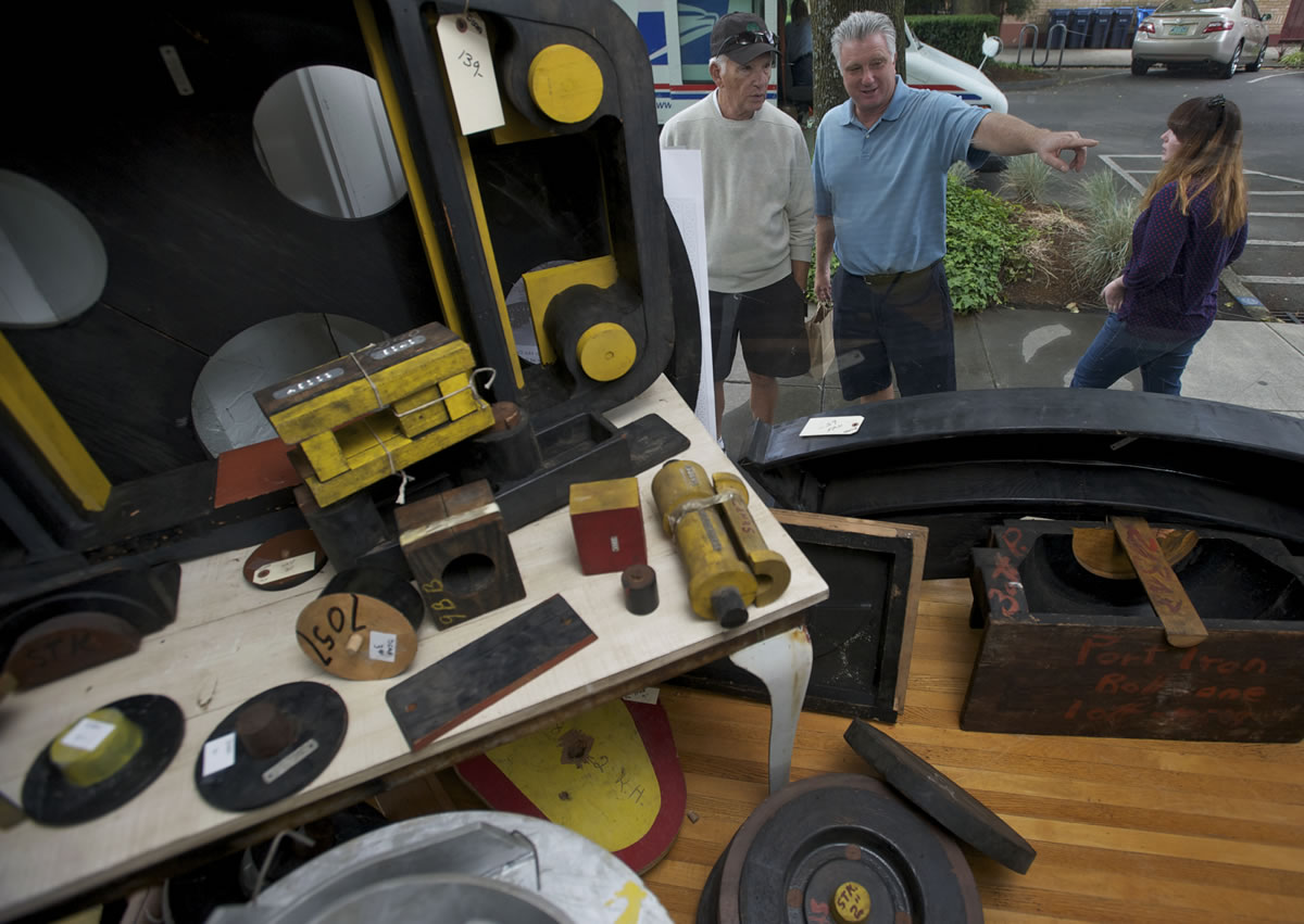 Chuck Lane, left, of Palm Desert, Calif., his son Daniel Lane of Camas and Annie Anderson of Oakland, Calif., look over a Camas Antiques display of wooden molds that were used to make machine parts.