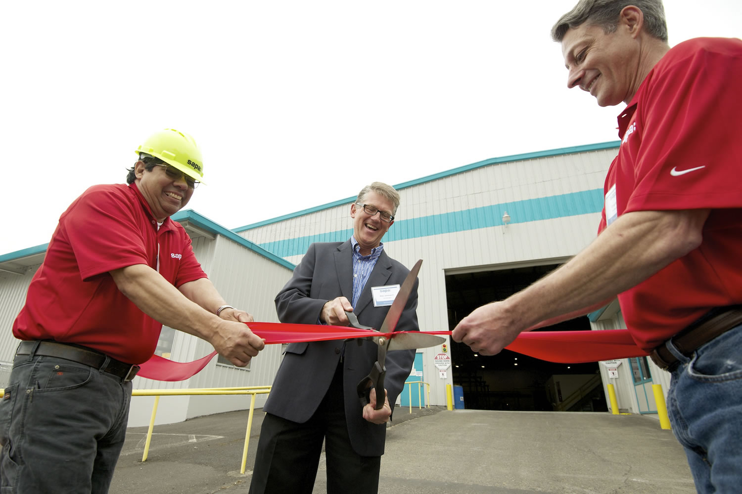 Pete Perez, facility manager at Sapa, from left, Mats Johansson, plant manager, and Greg Bartley, a die shop manager, cut the ribbon Friday to celebrate the opening of the company's new facility at the Port of Vancouver.
