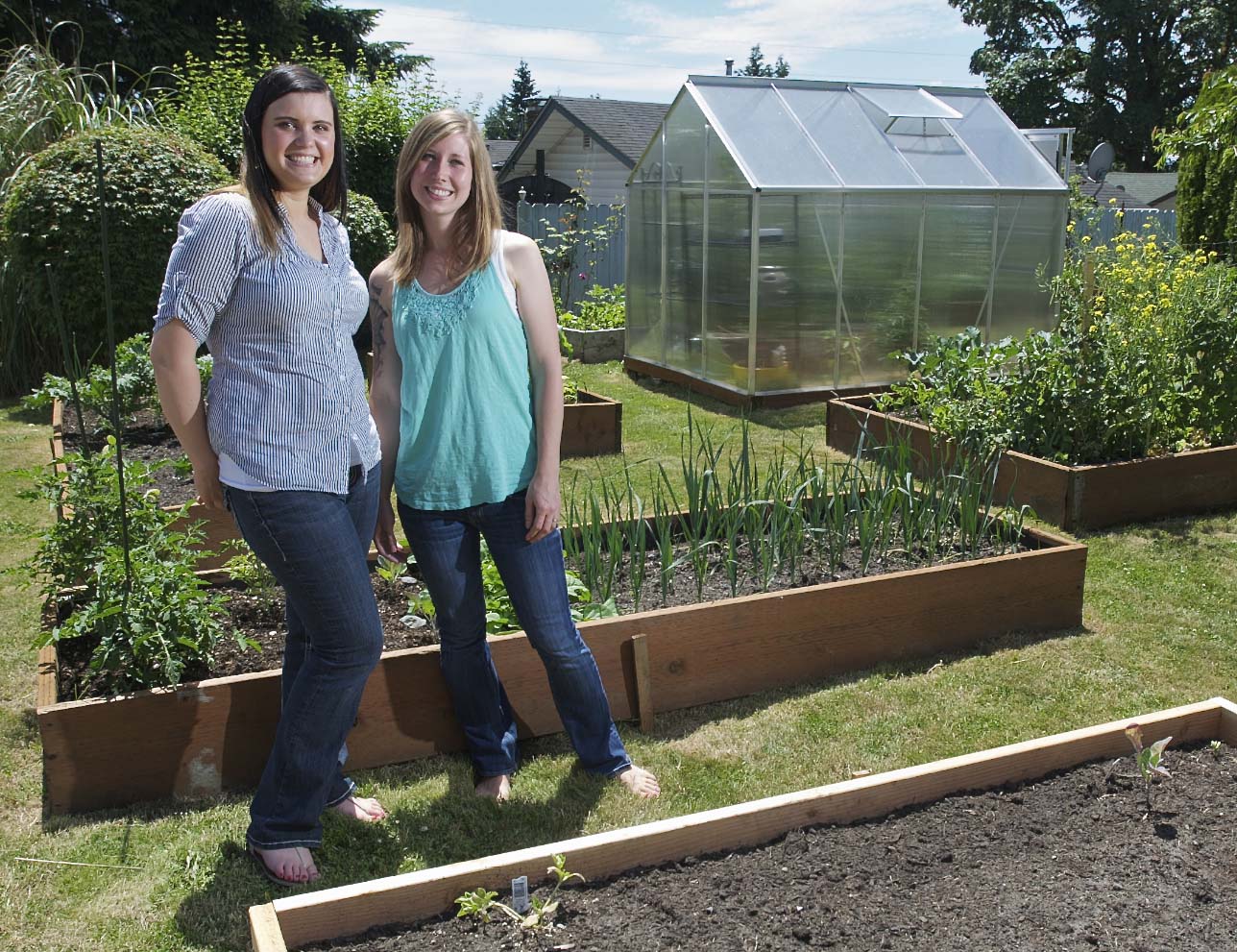 Omni Grover, right, and her best friend Kati Elliott stand next to Grover's urban garden, which includes a small greenhouse. The city cited Grover for the greenhouse because it's not in a backyard, but, with Elliott's help, she took the case to the Vancouver City Council and won. Consequently, rules regarding hobby greenhouses may be relaxed.