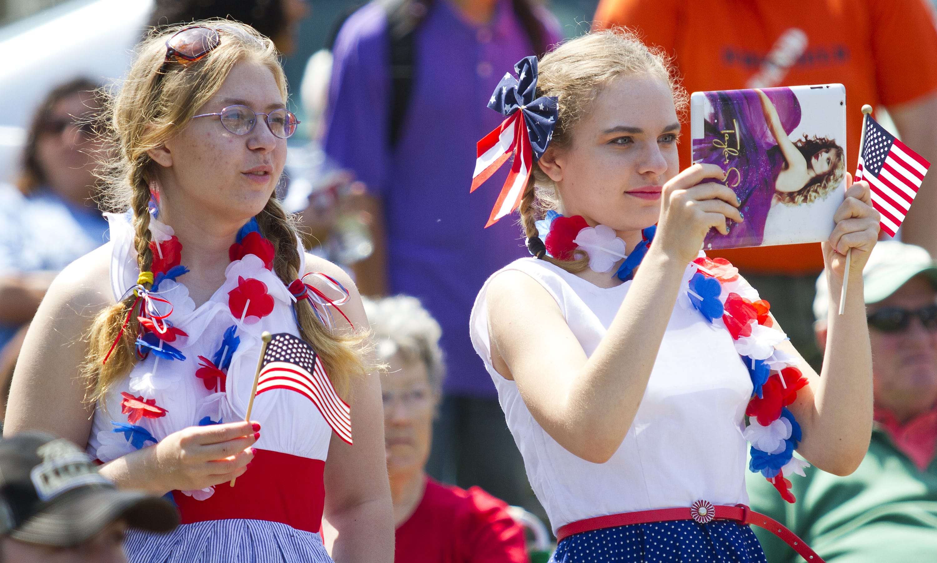Abby Storm, 14, waves her flag as Rachel Storm, 17, photographs the parade.