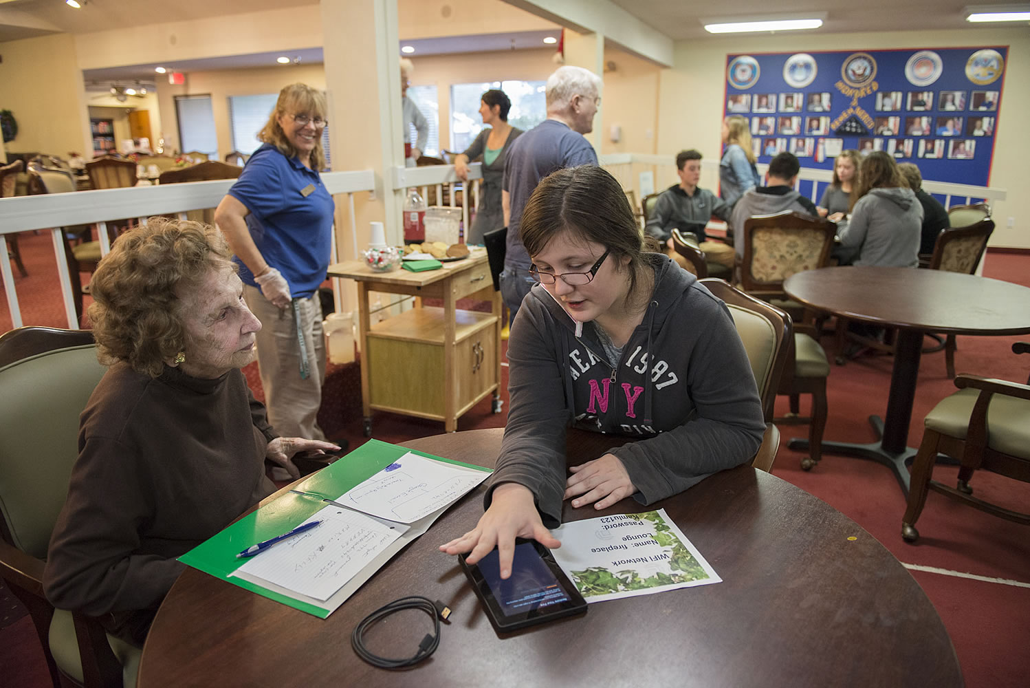 Marion Kelly, 92, left, looks to Covington Middle School eighth-grader Olivia Adams, 13, for advice on using her Kindle Fire at Kamlu Senior Living Center Monday morning.