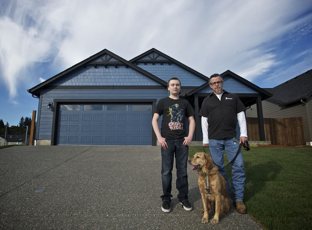 Tim Thornton, right, his stepson, Trevor Guttig, 14, and Bandit stand in front of the Woodland home they, along with Thornton's wife, Darcie Thornton, were set to move into at the end of this month. The U.S.