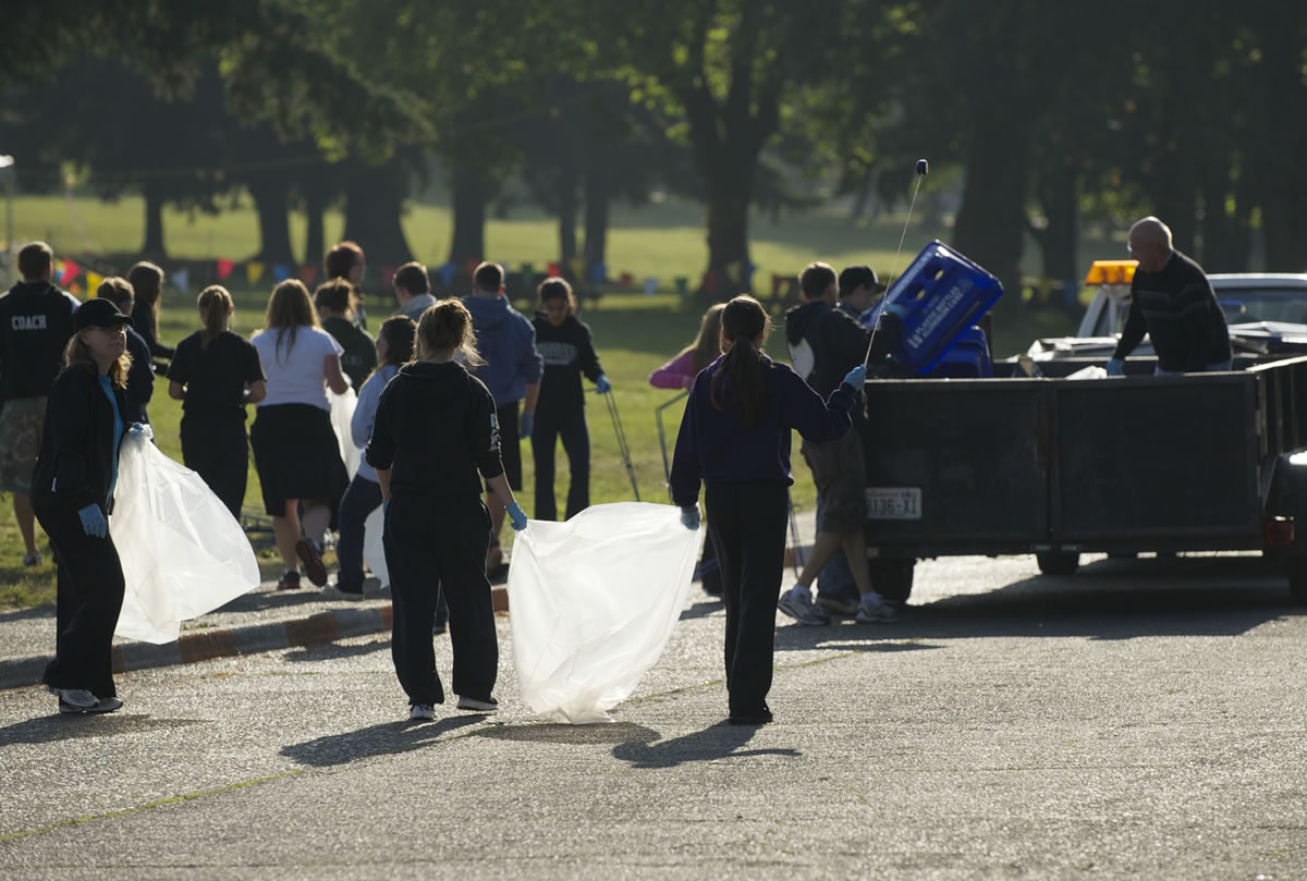 A crew made up of members of Woodland High School's golf, cheer and girls' soccer teams helps clean up Thursday morning after the Independence Day celebration at Fort Vancouver. About 40 athletes, parents and coaches arrived at 6 a.m., and by 8:30 a.m.