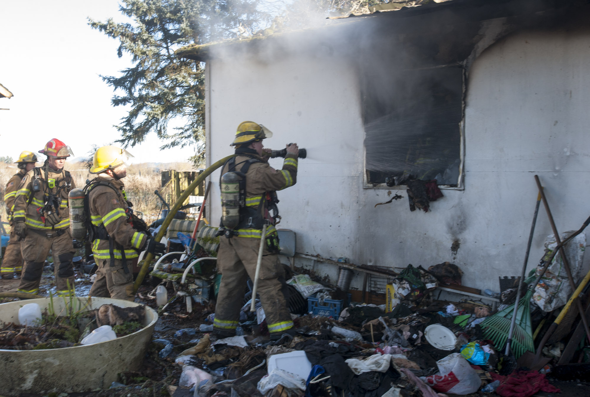 Firefighter Chase Christopher mans a hose as he and others battle a fire in a house in Battle Ground on Thursday.