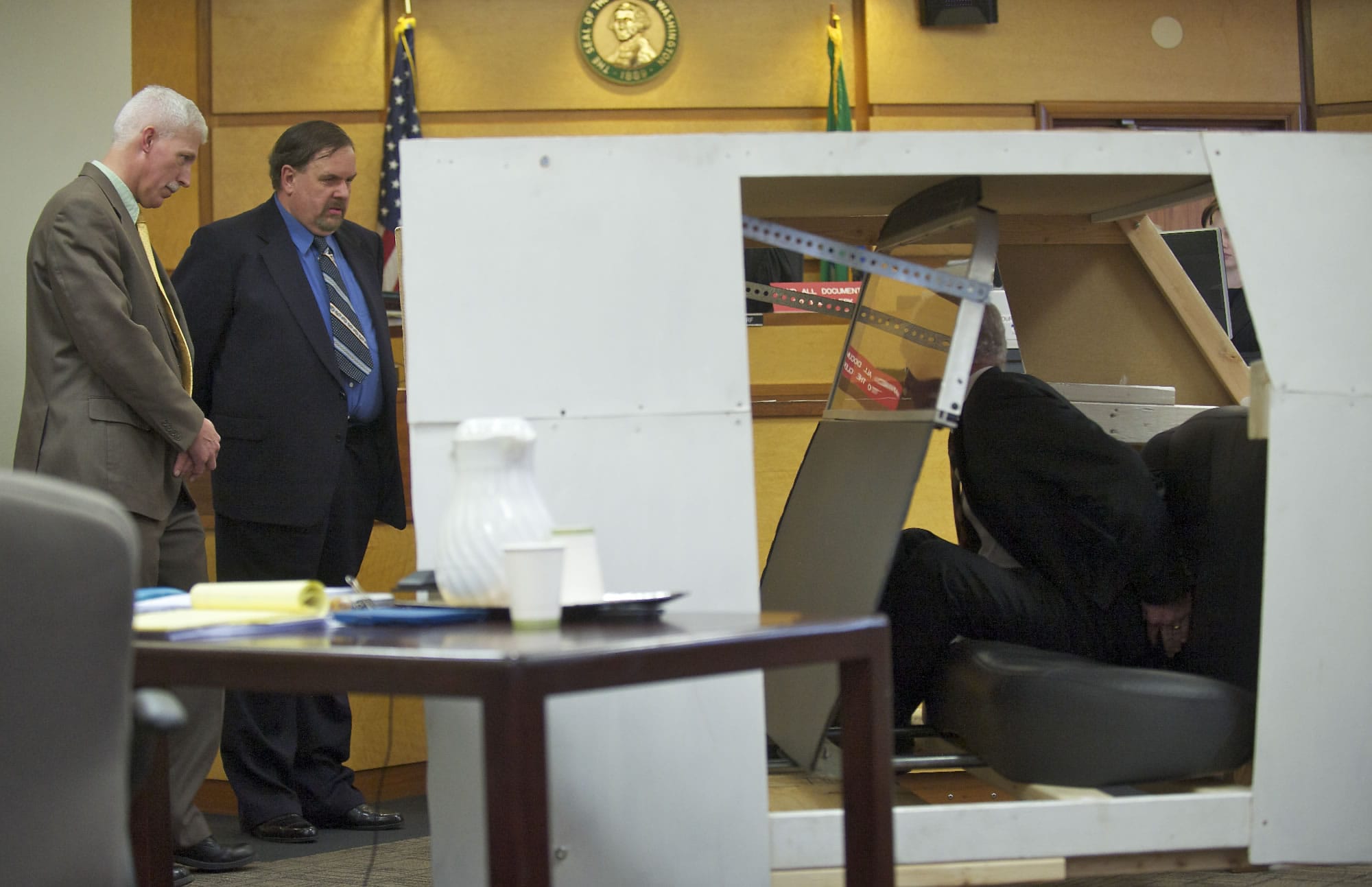 Defense expert witness Jim Pierce positions former Washougal police Officer Robert Ritchie, second from left, and his attorney, Jaime Goldberg, right, Thursday to re-enact what happened between Ritchie and Tyler Lampman inside a life-size model of Ritchie's patrol car.