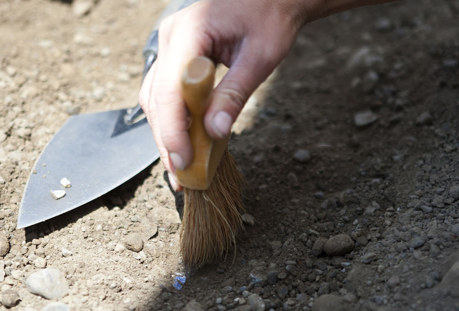 Caitlin Wichlacz, Washington State University Vancouver teaching assistant, brushes dirt from a ceramic fragment.
