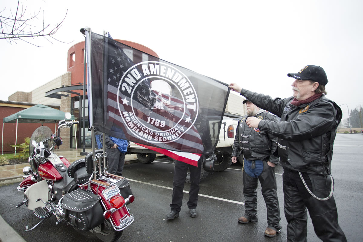 Barry Smith, a Patriot Guard rider from Rainier, Ore., shows the Second Amendment flag that hangs on the back of a motorcycle outside Coffee Villa in Vancouver, where gun supporters gathered for an open carry event Saturday.