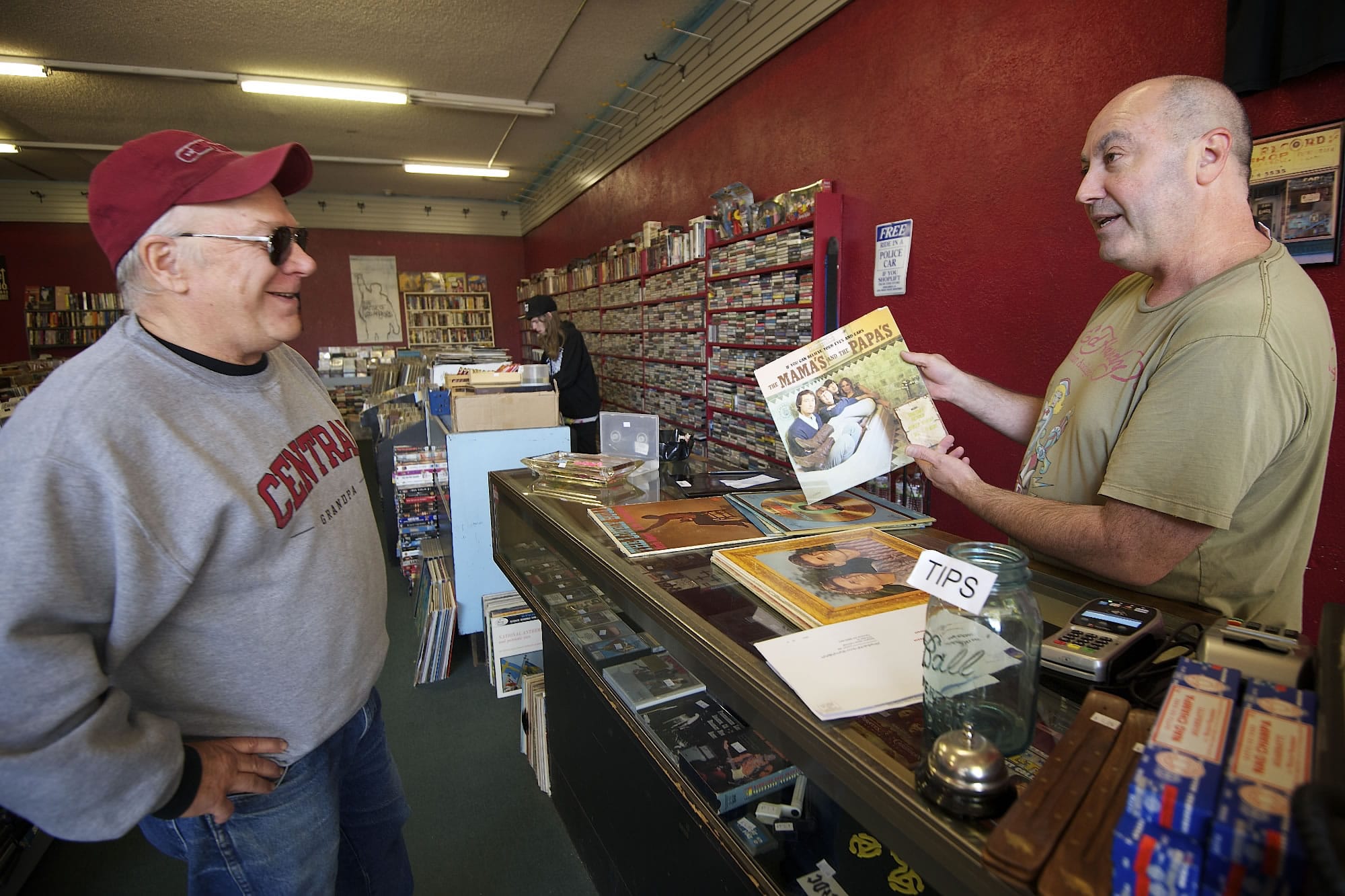 Brian Wassman, right, owner of Everybody's Music, explains the history of a record album's photo cover to customer Chip Bedord at the record store in Uptown Village he opened in 1992.
