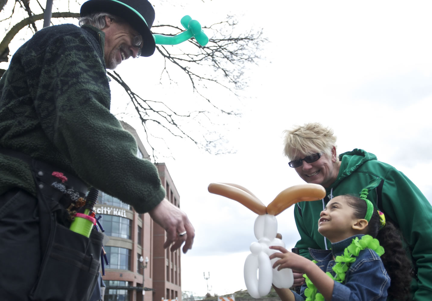 Kaiya Langseth, 5, of Vancouver receives a balloon dog from balloon artist Jim Healey at the Vancouver Farmers Market on Sunday. Watching the happiness is her grandmother, Molly Zinda. Kaiya exclaimed, &quot;Happy St.