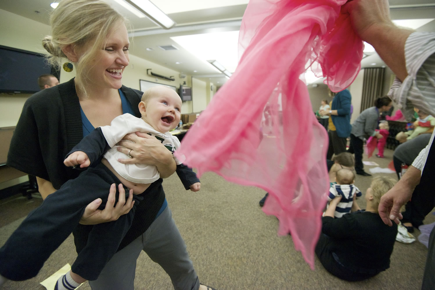 Heather Stuart, left, and her 7-month-old son, Obadiah, laugh as dad Steve Stuart, a Clark County commissioner, playfully waves a pink scarf during the &quot;Love, Talk, Play&quot; event Thursday at the Center for Community Health in Vancouver.