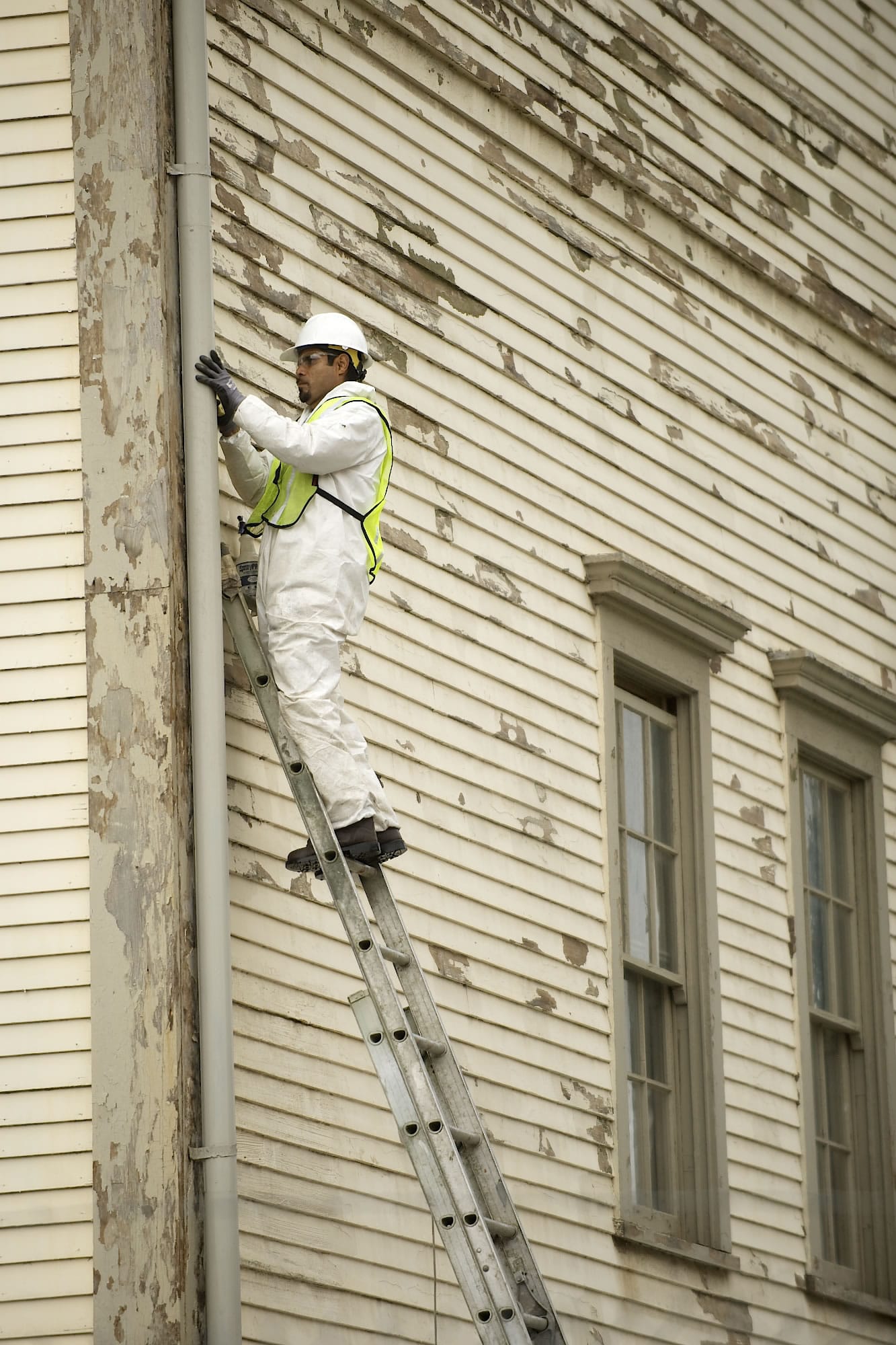 Bernabe Flores, a painter with DSL Builders, removes peeling lead-based paint by hand Wednesday from the Vancouver Barracks headquarters building.