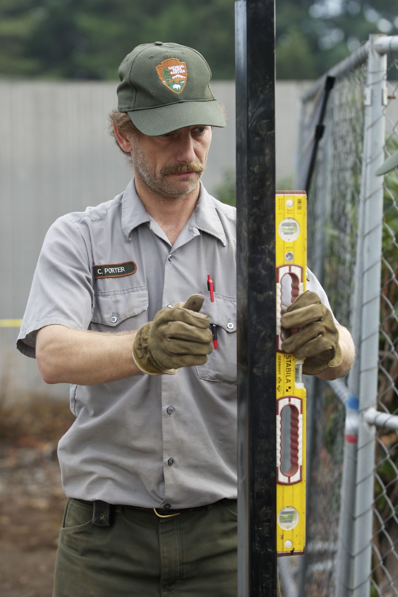 National Park Service employee Cary Porter checks a fence post for plumb Thursday during the construction of a new fence around Vancouver's Old Apple Tree.