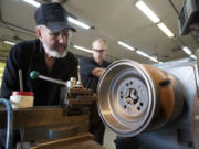 Quality Machine owner Bob Fuller, left, and shop foreman Brian Kinnaman use a lathe to customize a brake drum for a customer.