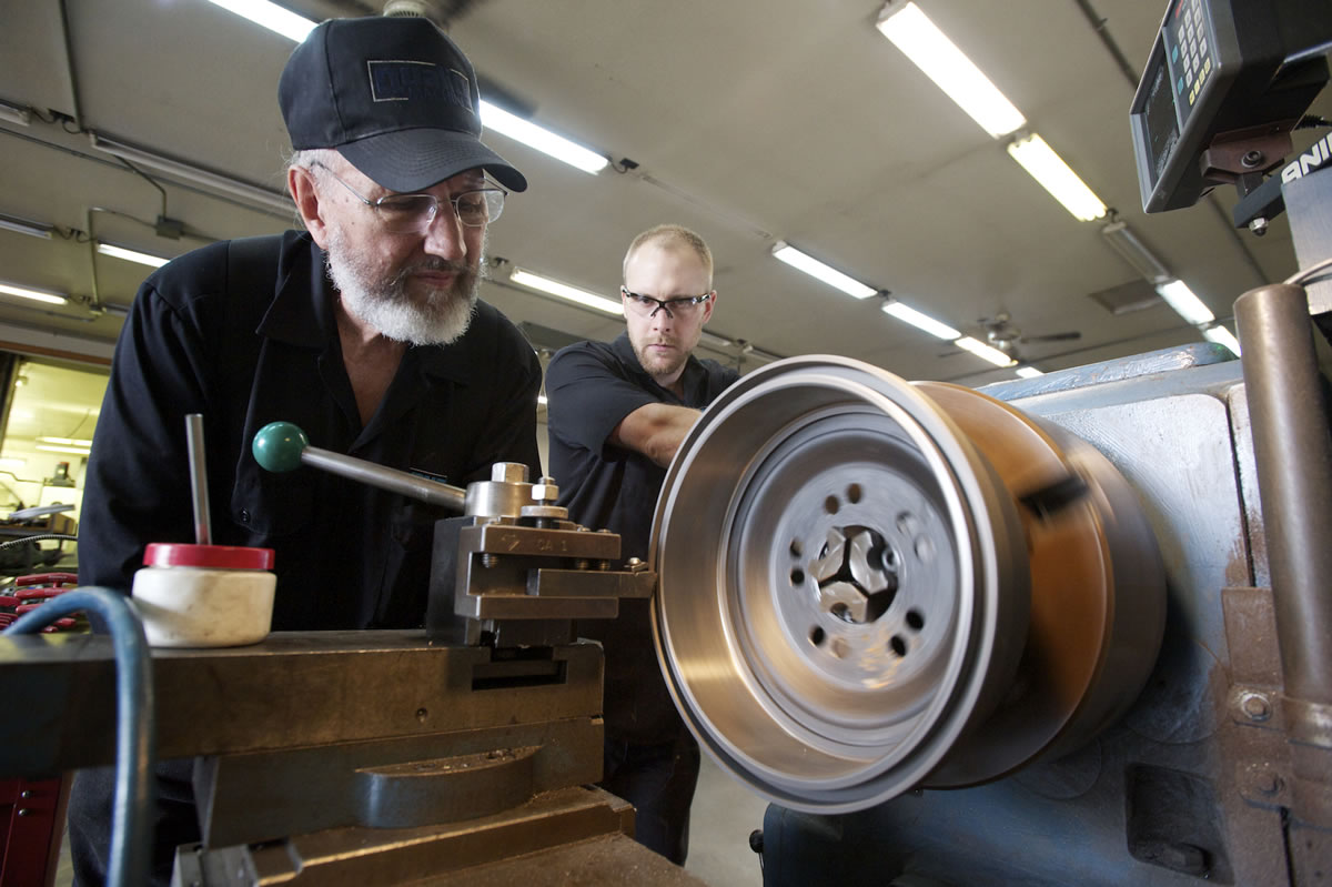Quality Machine owner Bob Fuller, left, and shop foreman Brian Kinnaman use a lathe to customize a brake drum for a customer.