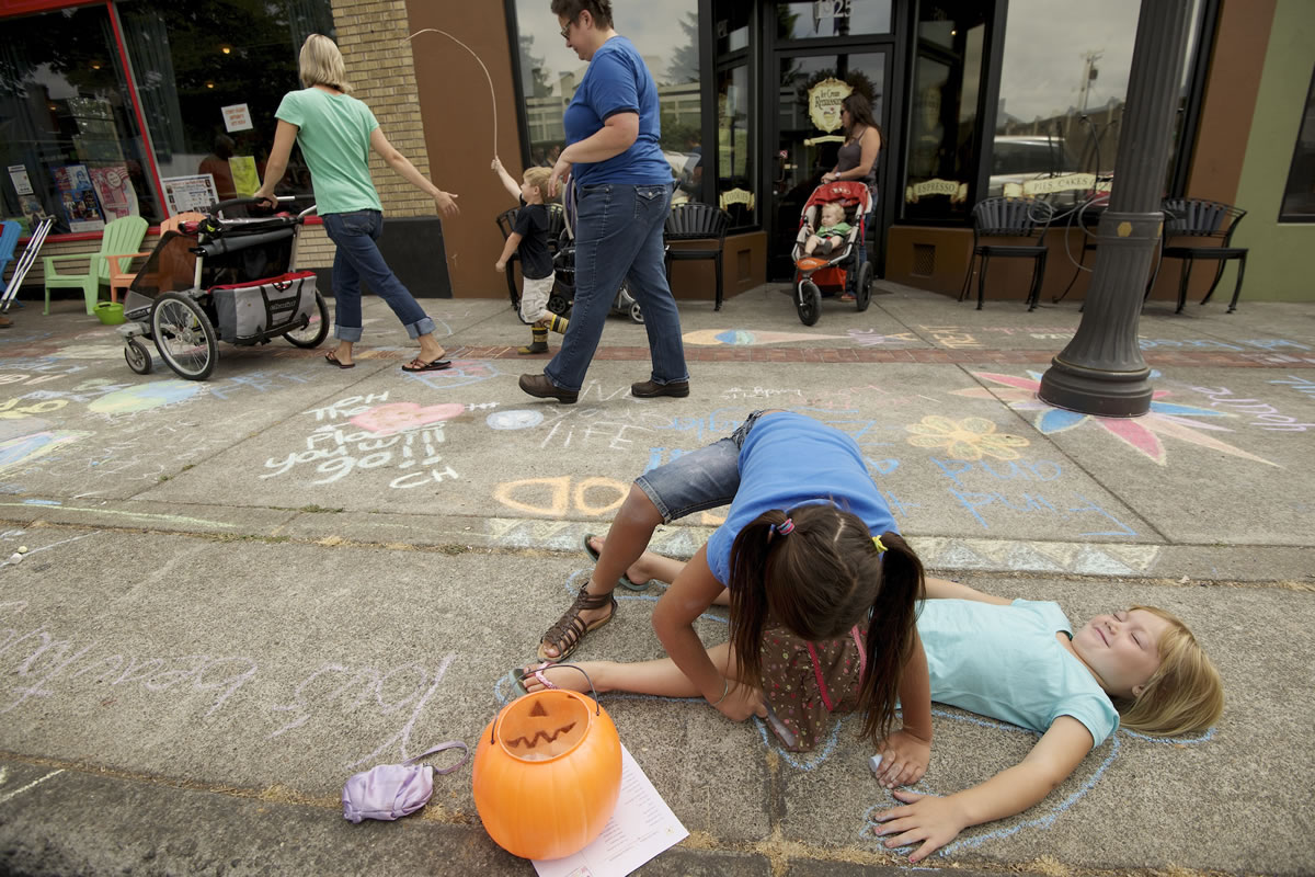 Sophie Albright, 8, uses chalk to trace around her friend, Chloe Schafer, 5, during the second annual Chalk the Walks, a project of the Joy Team. Top: Jay Morton, 24, a 2006 graduate of Vancouver School of Arts and Academics, works on a chalk drawing on an Uptown Village sidewalk.