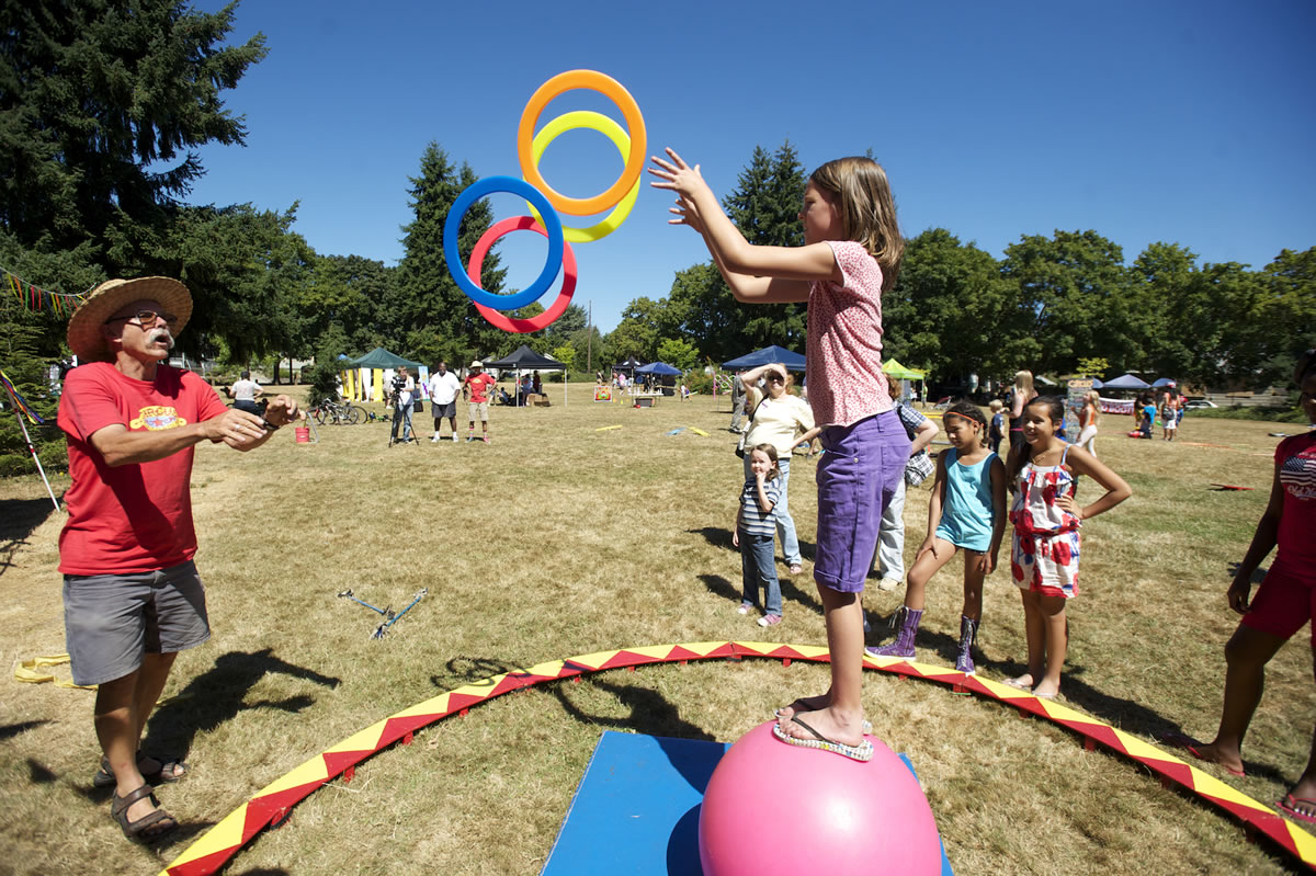Ellie Johnson, 8, plays a hoop game with Bill Hewitt of Circus Cascadia while balancing on a ball at John Ball Park during the Sunday Streets Alive event.
