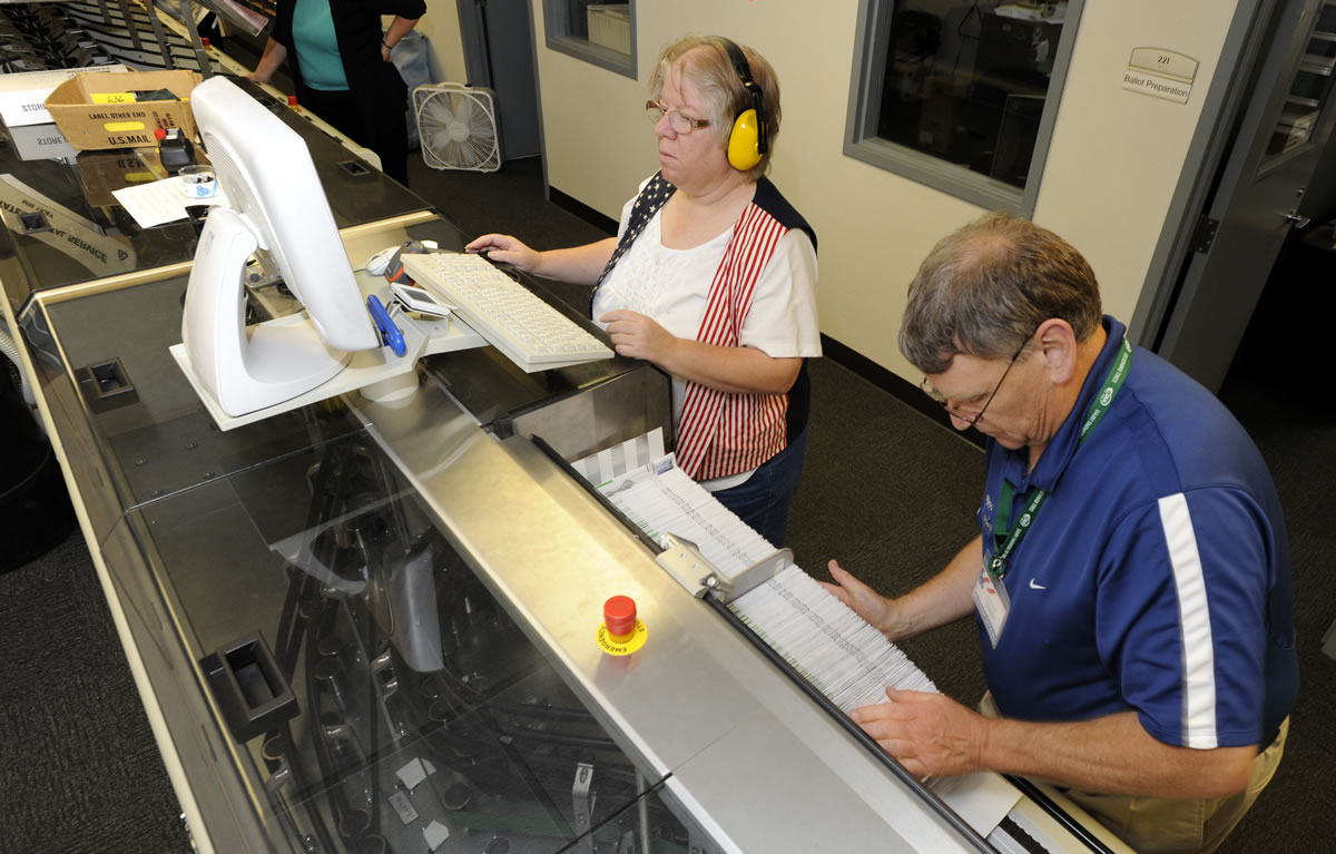 Election officers including Wendy Wimer, top, run the machine for sorting ballots at the Clark County Elections Office in Vancouver on Tuesday.