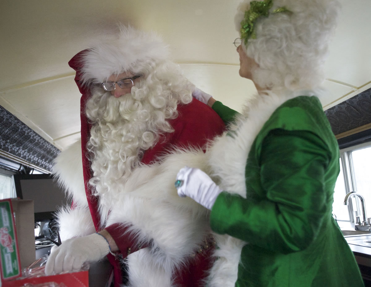 Phillip Verry, aka Santa Claus, gets help with his outfit from Dee Campbell, aka Mrs.
