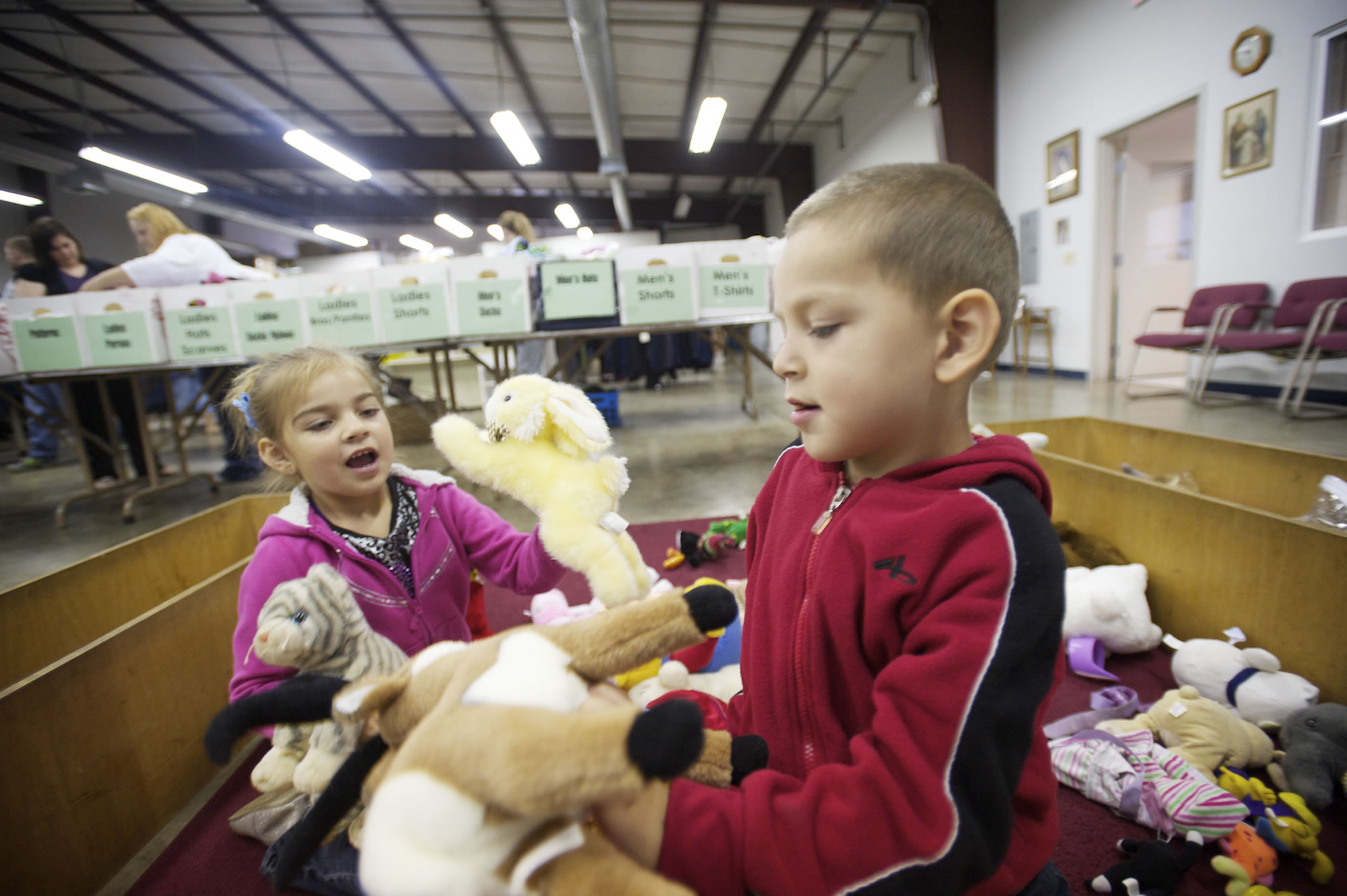 Emilia, 5, and Chico, 4, play with stuffed animals as their mom, Jessica Fraly, looks for school clothing at the St. Vincent de Paul food and clothing bank.