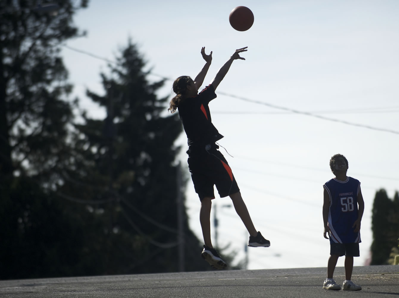 Marcus Cadiz, 13, and his brother, Malokai Cadiz, 9, enjoy Sunday's warm weather as they shoot hoops at the home of their grandmother, Martha Gates of the Northwest neighborhood.