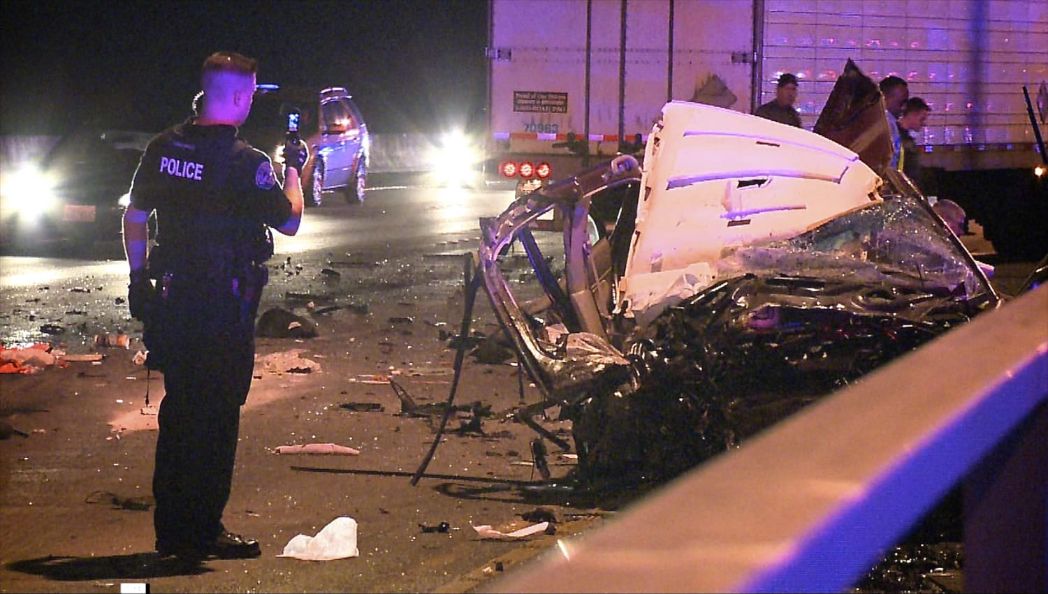 A police officer examines the remains of a Vancouver woman's car destroyed by a wrong-way truck, background, on the Interstate 205 bridge. The trucker was arrested; the car's driver had only minor injuries.