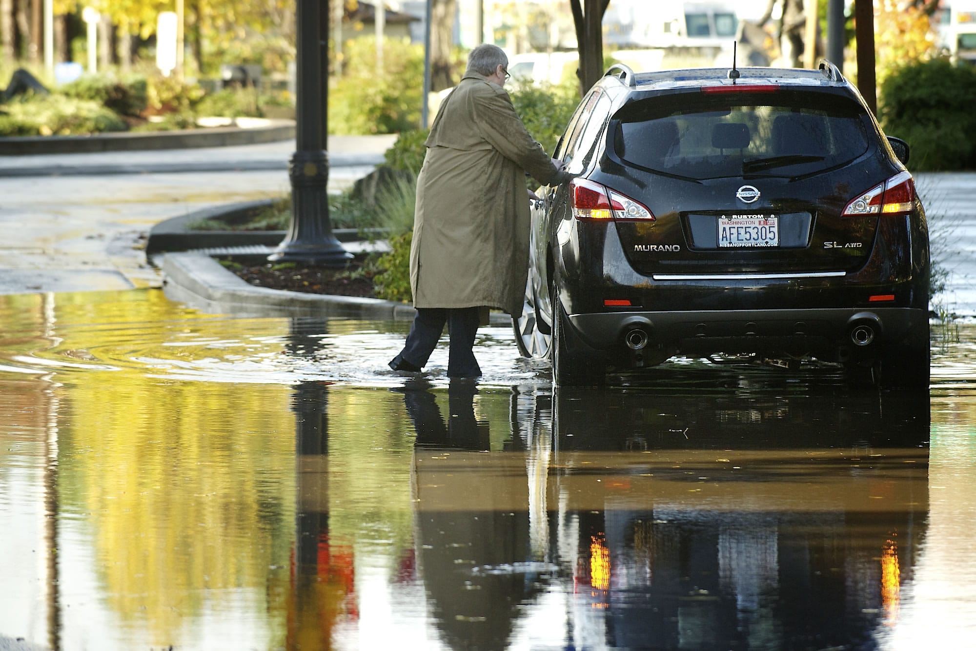 A motorist gets his feet wet Tuesday as he braves a new body of water on West Sixth Street in Vancouver.