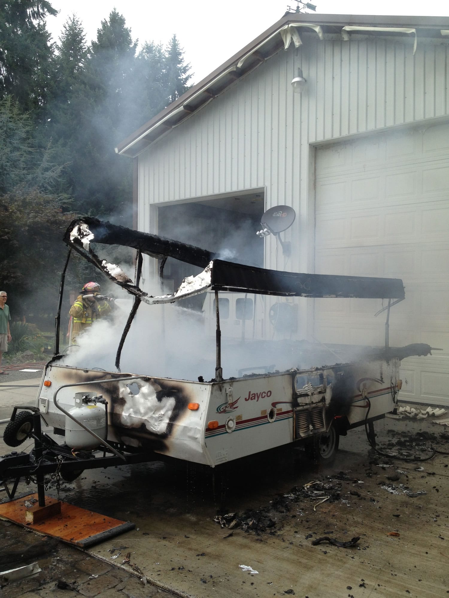 Firefighters spray down a pop-up camping trailer that caught fire at a residence in Ridgefield.