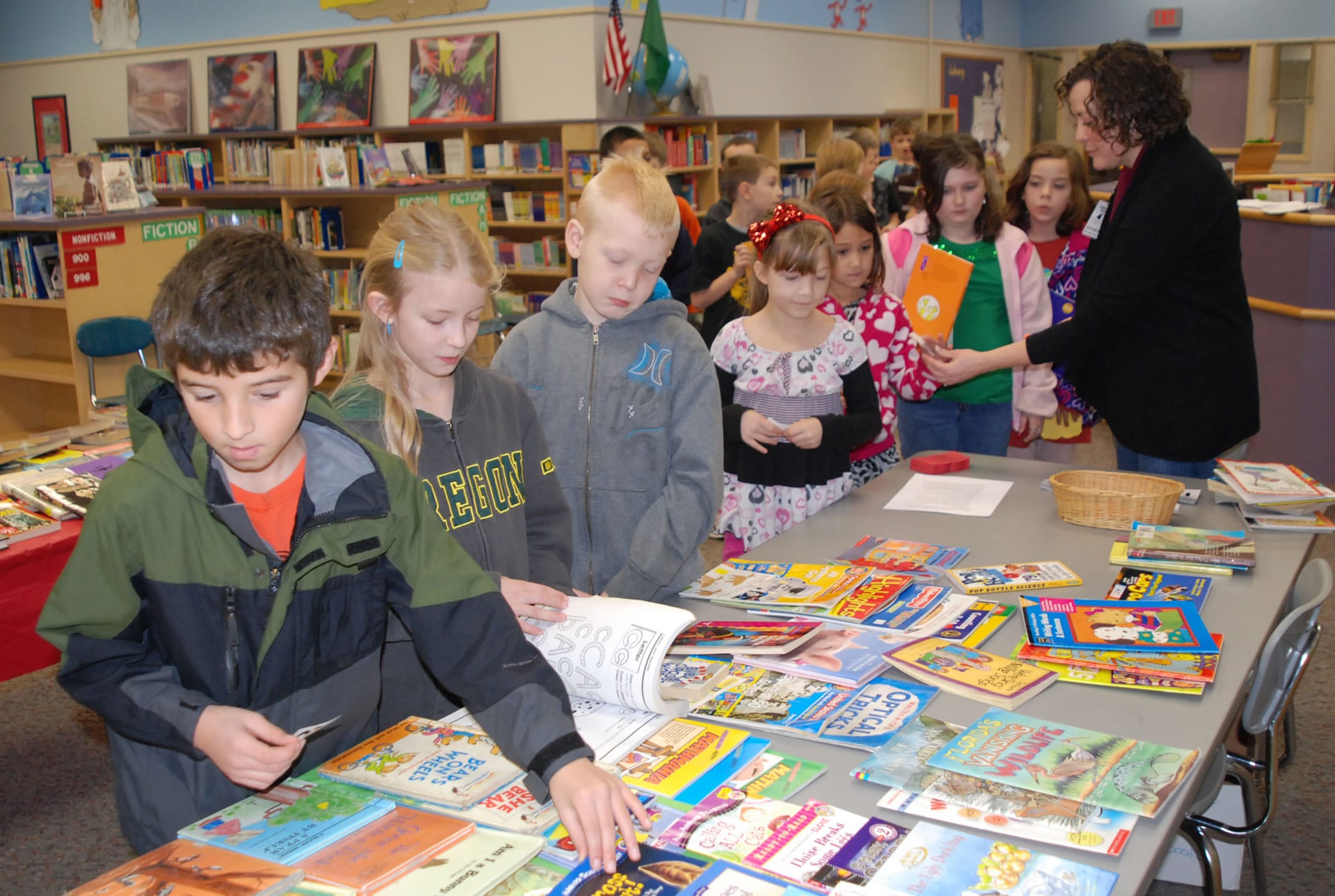 Washougal: Hathaway Elementary Booster Nancy Kutchera helps students pick out new reads at the school's Trade-a-Book program.