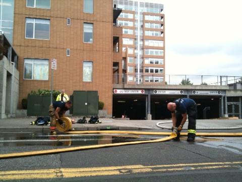 Firefighters roll up their hoses after extinguishing a vehicle fire in the underground garage at Vancouvercenter today.