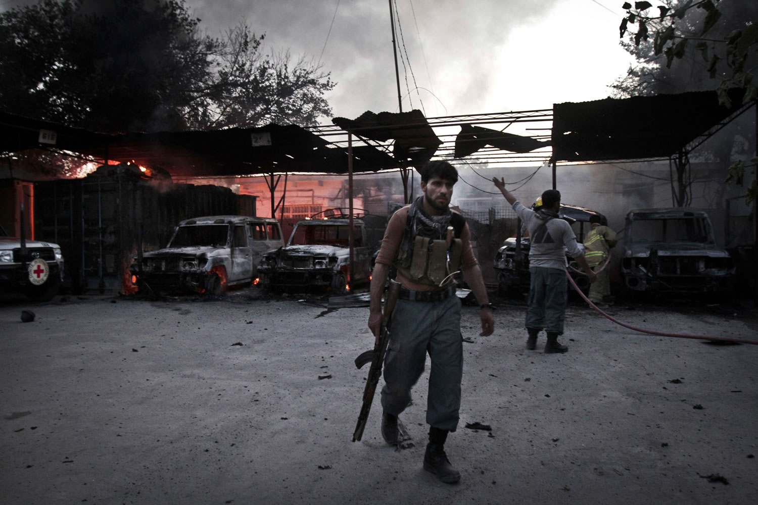 An Afghan policeman is seen at the burning International Red Cross building during a gun battle between security forces and an insurgent in Jalalabad east of Kabul, Afghanistan, on Wednesday.