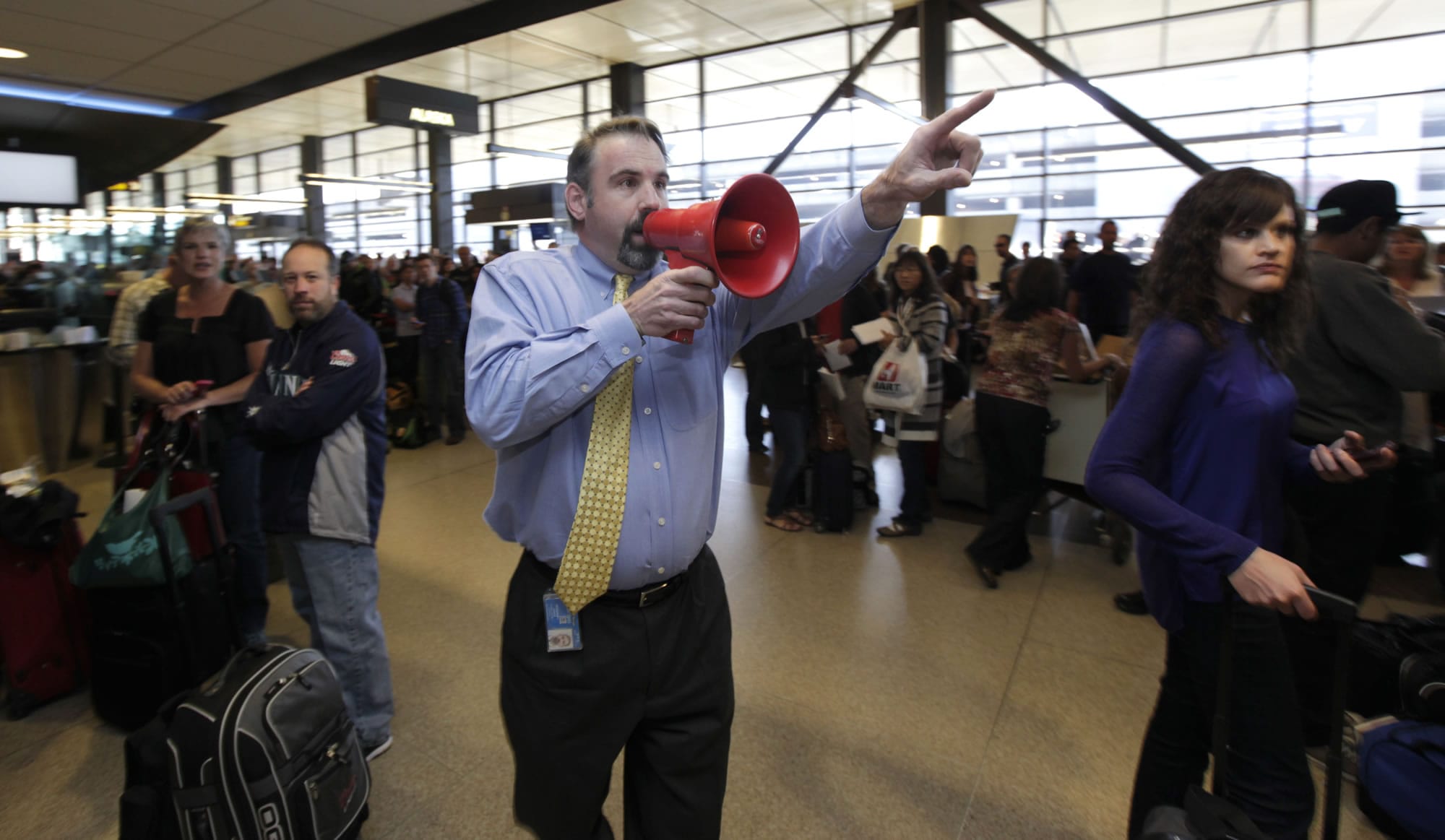 Jim McBarron, manager of station operations for Alaska Airlines at Seattle-Tacoma International Airport, uses a bullhorn to try and find passengers for a flight that was about to take off for San Diego on Monday.
