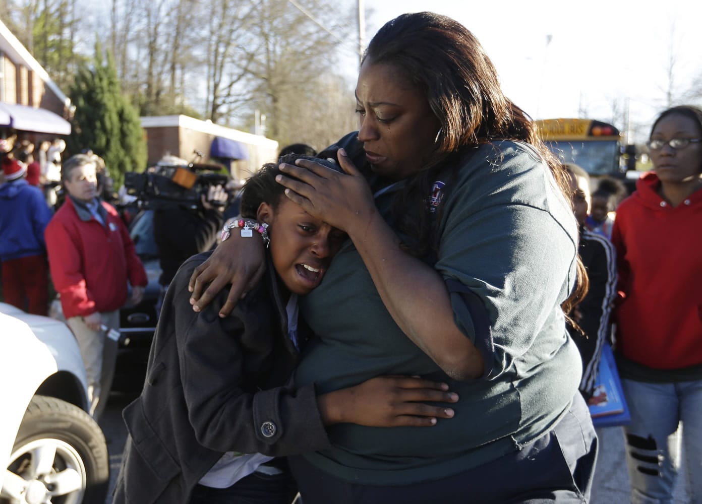 A woman comforts a child after after a shooting at Price Middle school in Atlanta on Thursday. A 14-year-old boy was wounded outside the school Thursday afternoon and a fellow student was in custody as a suspect, authorities said.