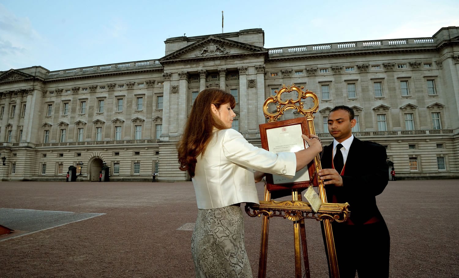 The Queen's Press Secretary, Ailsa Anderson, and Badar Azim, a footman, place an official document to announce the birth of a baby boy to William and Kate, the Duke and Duchess of Cambridge, in the forecourt of Buckingham Palace in London on Monday.