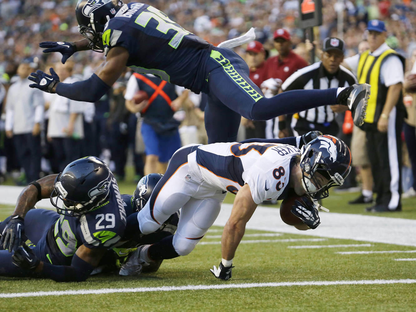 Denver Broncos wide receiver Wes Welker scores a touchdown under the defense of a leaping Seattle Seahawks cornerback Brandon Browner (39) and tackles by Seahawks' Earl Thomas (29) and Antoine Winfield (obscured) in the first half of a preseason NFL football game, Saturday, Aug. 17, 2013, in Seattle.