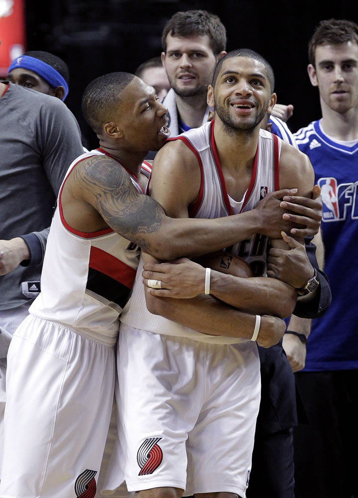 Portland Trail Blazers guard Damian Lillard, left, hugs teammate Nicolas Batum after winning an NBA basketball game against the Los Angeles Clippers in Portland, Ore., Saturday, Jan. 26, 2013.  Both players scored 20 points each as the Trail Blazers won 101-100.