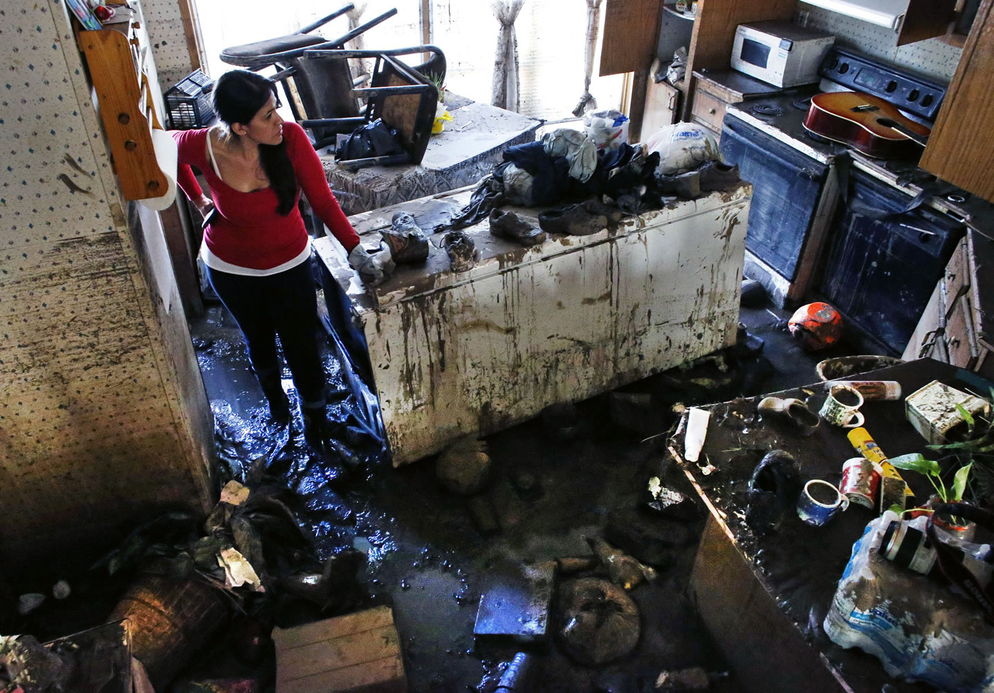 Sonia Marquez, an organizer with the Colorado Immigrant Rights Coalition, looks for keepsakes Tuesday inside one of the many mobile homes now declared uninhabitable due to flood damage at a decimated trailer park in Evans, Colo.