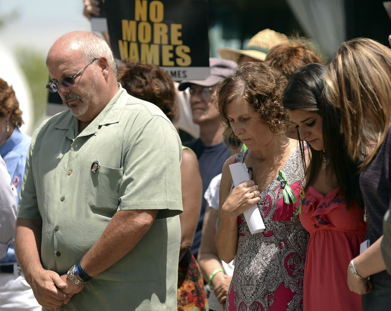 From left, Tom Sullivan, father of Aurora shooting victim Alex; Jane Dougherty, sister of Sandy Hook elementary school shooting victim Mary Sherlach; Carlee Soto, sister of Sandy Hook elementary school shooting victim Victoria; and Coni Sanders, daughter of Columbine High School shooting victim Dave Sanders, stand together during an event to honor those killed in the massacre at an Aurora, Colo. movie theater a year after the attack on Friday in Arapahoe County, Colo.