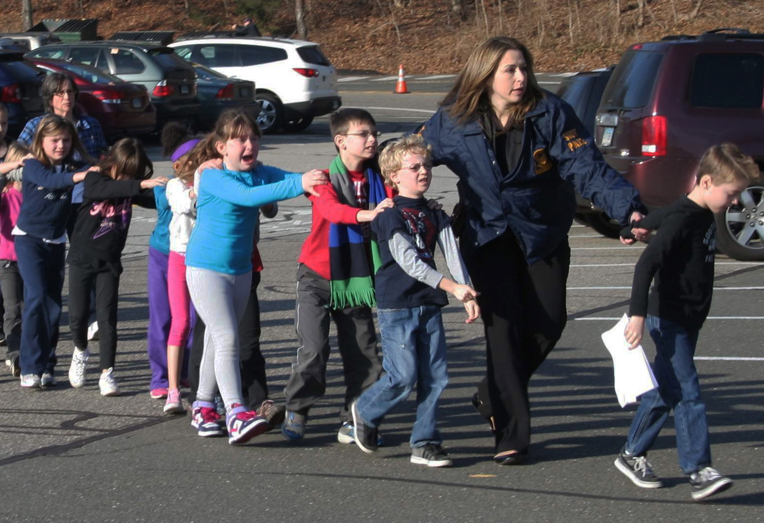 A Connecticut State Police trooper leads children away from Sandy Hook Elementary School after Friday's shooting in Newtown, Conn.